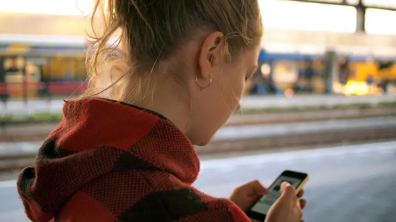 Woman texting on her smartphone at a train station